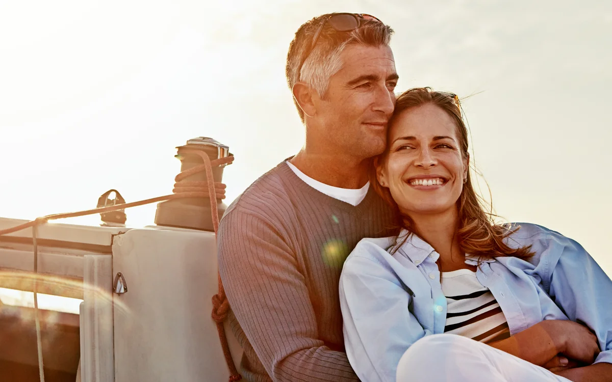 Couple at ease aboard a sailing yacht at golden hour